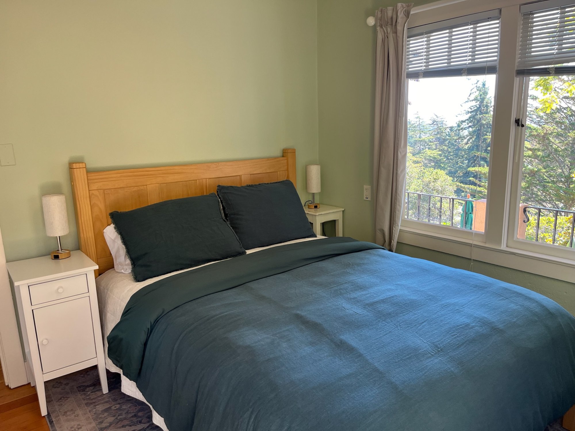 Bright queen bedroom with hardwood floors and garden views