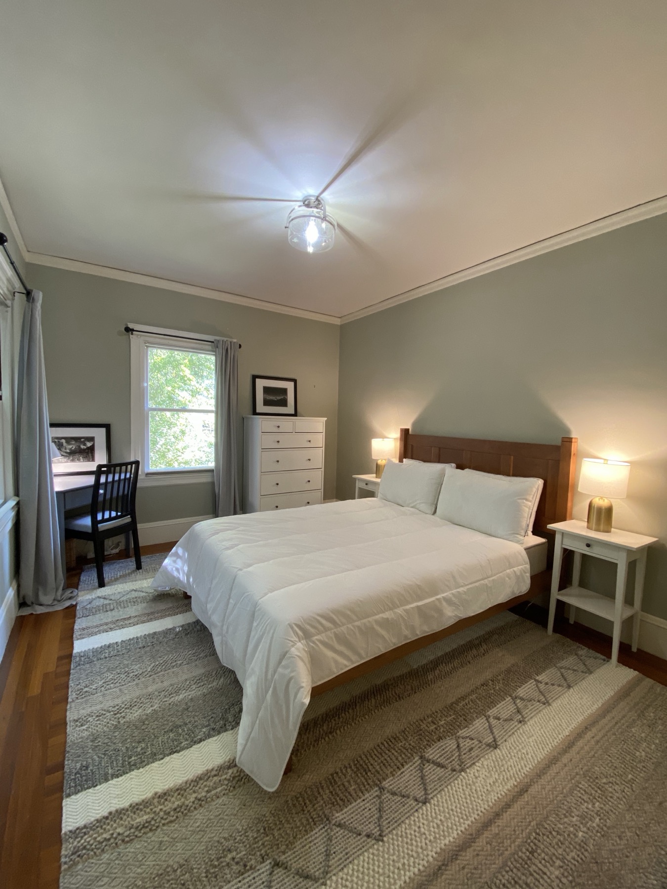 Queen bedroom with hardwood floors, chandelier, and garden view