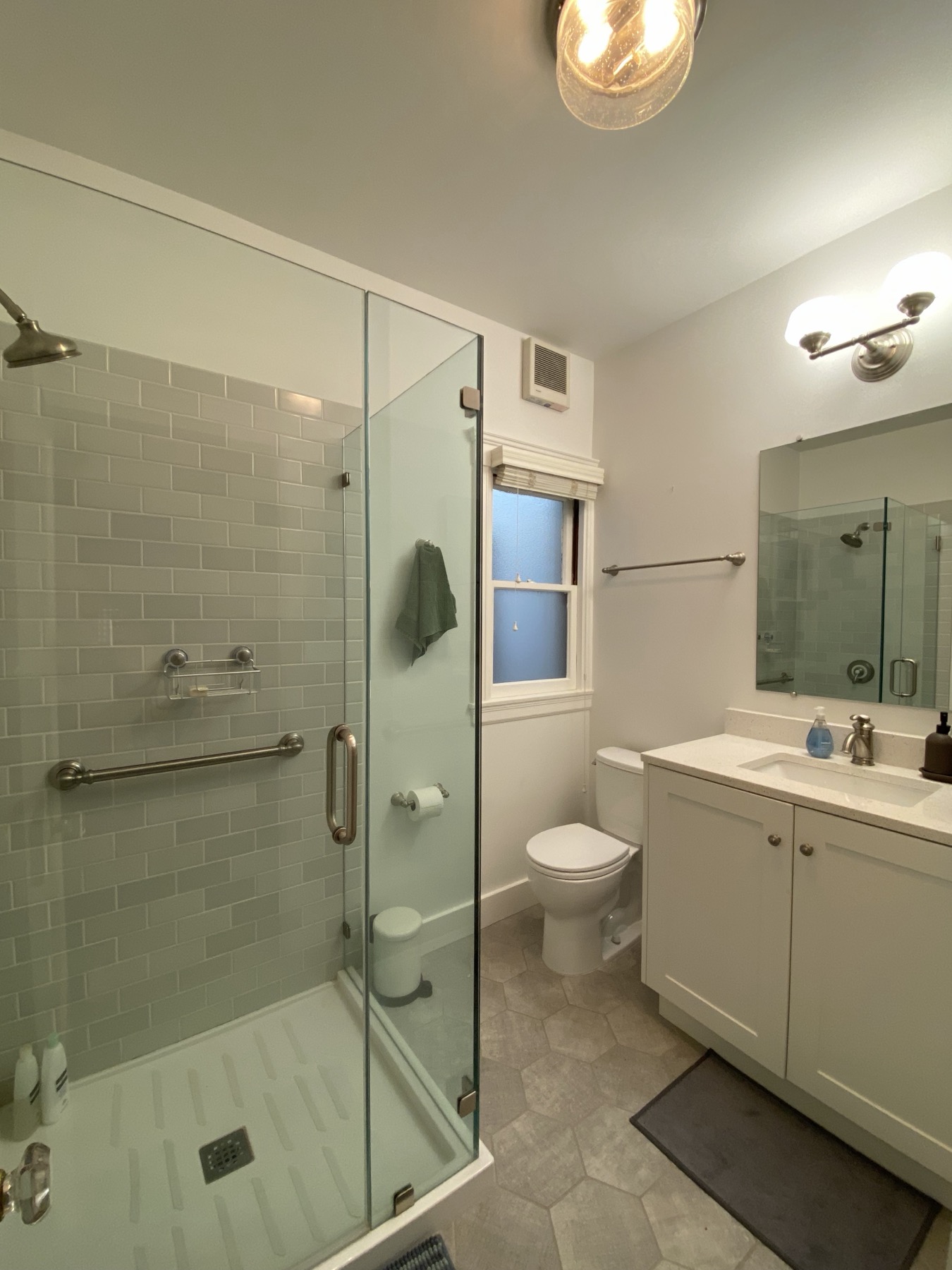 Renovated bathroom with glass-enclosed shower and vanity