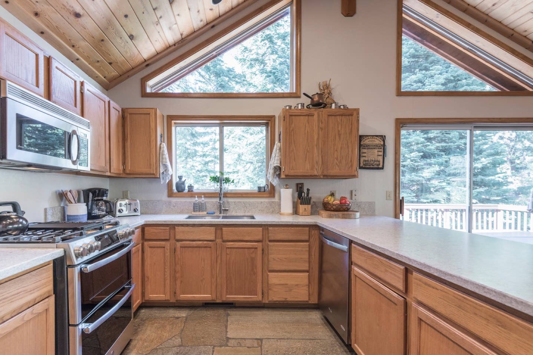 Kitchen with gas range, stainless appliances, and forest views