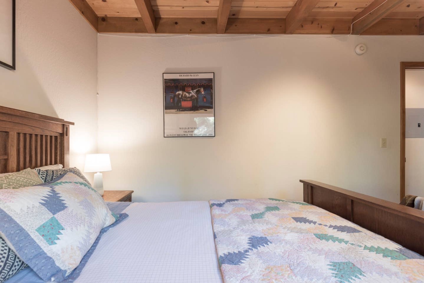 Bedroom with quilted bedding and Tahoe landscape art
