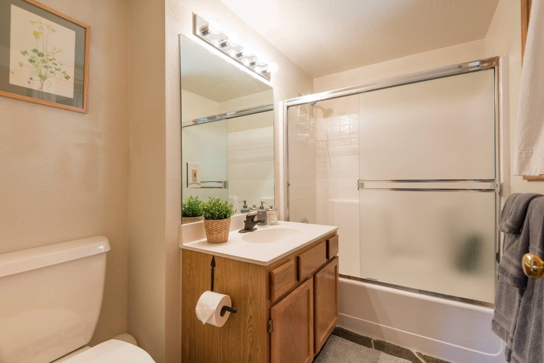 Clean bathroom with tub/shower and framed mirror